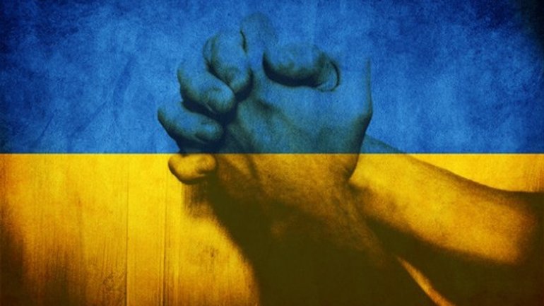Knäppta händer med Ukrainas flagga i bakgrunden